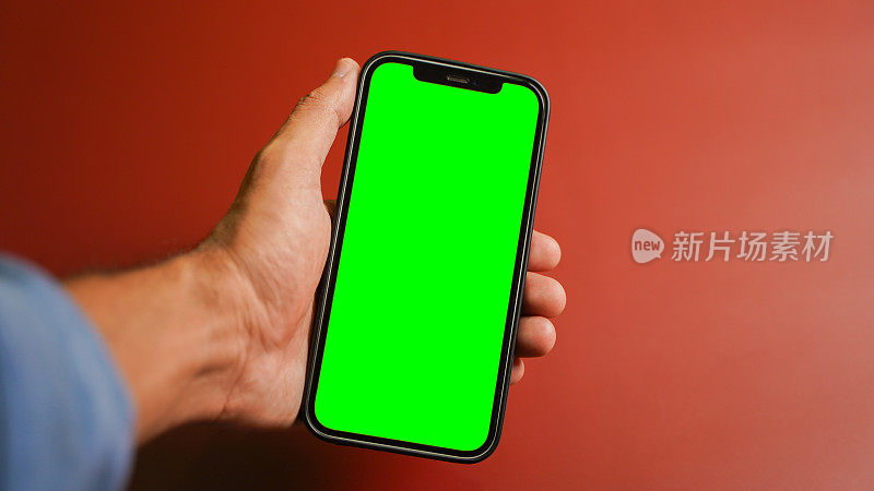 手持手机，空白的绿色屏幕平放，智能手机隔离在彩色背景上