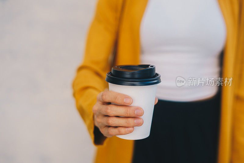 特写一个女人的手拿一个纸咖啡杯