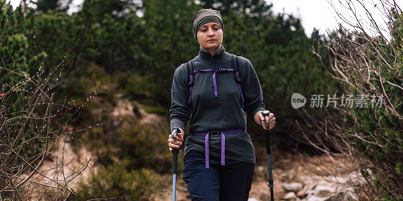 女人的女性肖像，谁在山中旅行。穿着保暖运动服在户外徒步旅行的人。生活方式摄影的人物和北欧徒步，旅游的概念。女孩是背包客，背包里装着旅游装备。