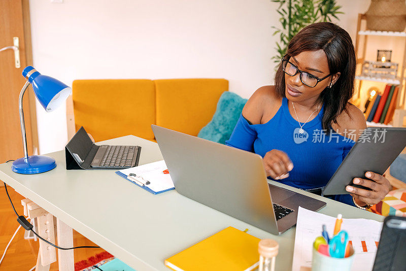 年轻的黑人女性在家里用数码平板电脑学习