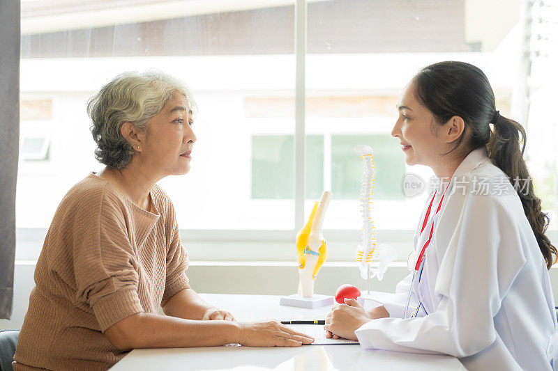 家庭医生在医院用听诊器检查微笑的亚洲老妇人一位老妇人正在向医生咨询整骨病的问题。健康及健康概念