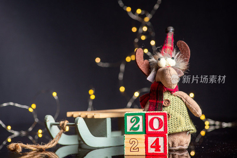 2024年新年喜庆的背景与木制数字显示即将到来的一年和圣诞节的象征软驯鹿玩具旁边的雪橇