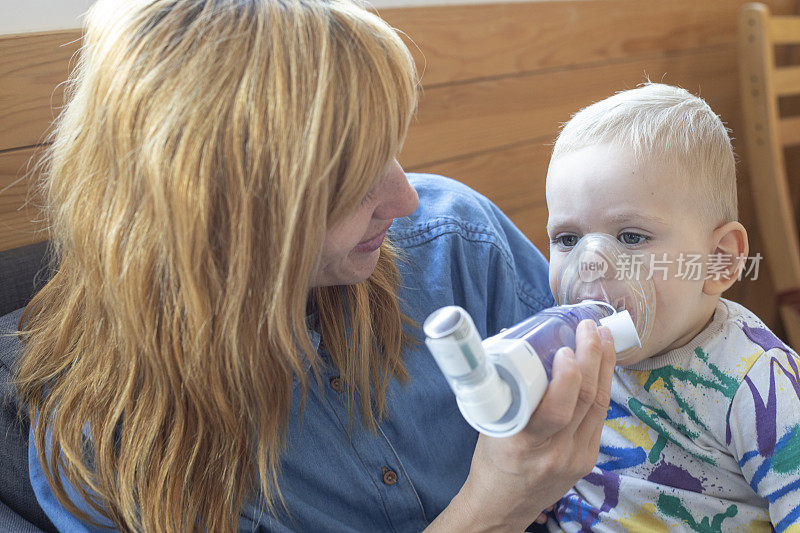母亲用吸入器帮助患有哮喘病的婴儿