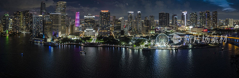 迈阿密观景轮在夜晚照耀着佛罗里达州比斯坎湾的海滨。游艇和船只停泊在码头上