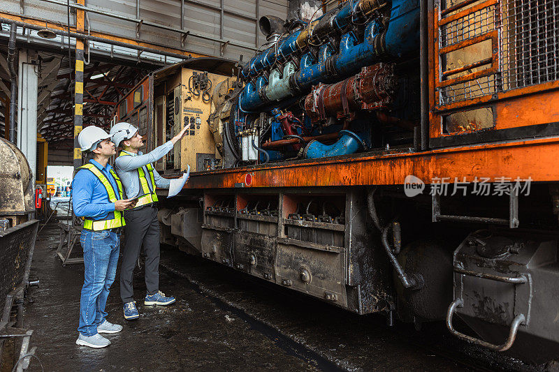 专业工程师工人看着老旧的润滑脂油脏的大型机车发动机计划大修服务。柴油火车发动机服务。