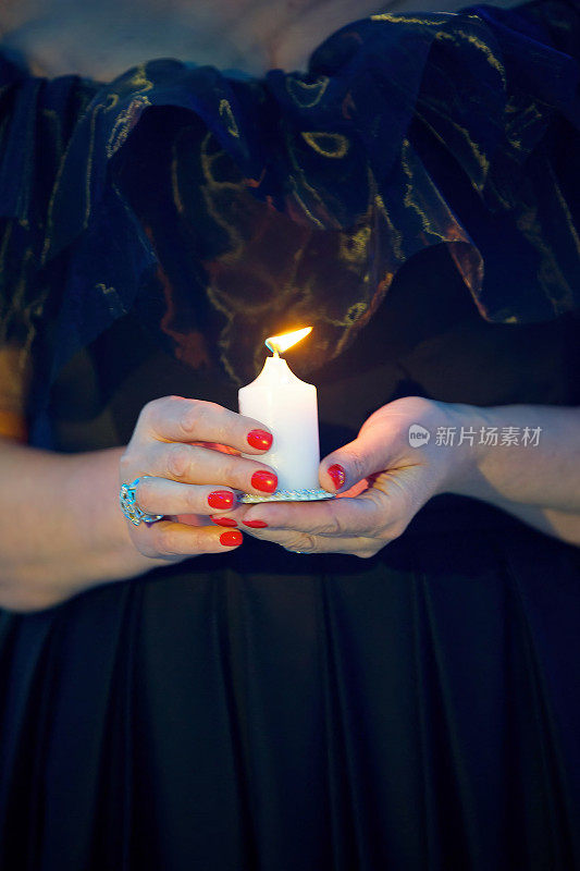 女人手中的蜡烛。神秘和神秘。节日圣火