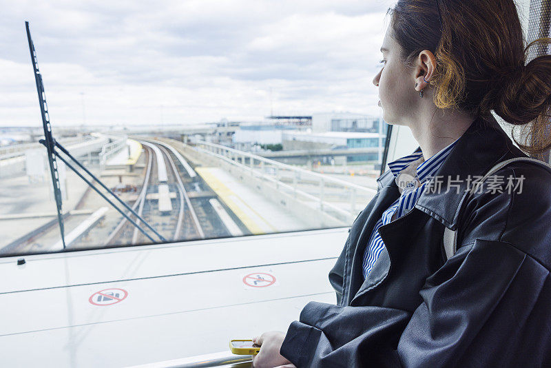 在机场候机厅等火车。一名女子在机场自动铁路上望向窗外