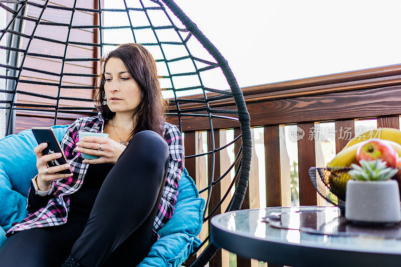 这是属于我自己的时刻。一位女士正坐在阳台上的秋千椅上享受下午的休息。