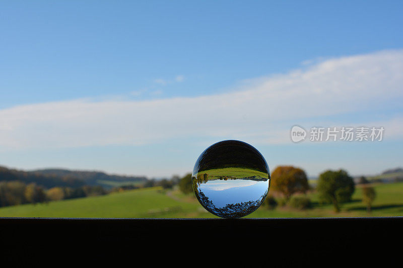 绿色的风景映在一个球体上，配上蔚蓝的天空