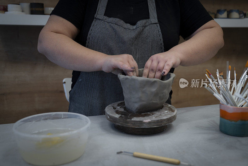 女陶工在陶轮上用湿粘土制成的围裙状花瓶里