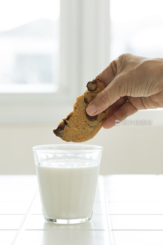 把饼干和巧克力片浸在一杯鲜牛奶里