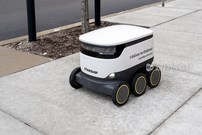 在美国宾夕法尼亚州匹兹堡市的匹兹堡大学校园里，一个Starship送餐机器人正在人行道上行驶