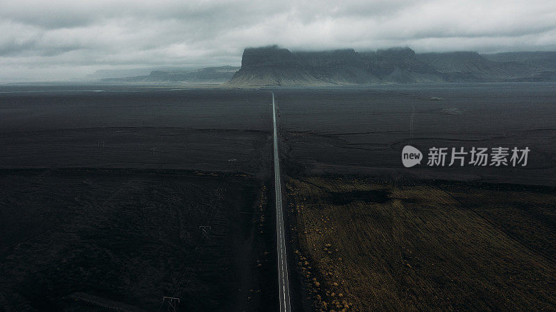 戏剧性的鸟瞰图的汽车驾驶的道路与风景的山在喜怒无常的一天在冰岛