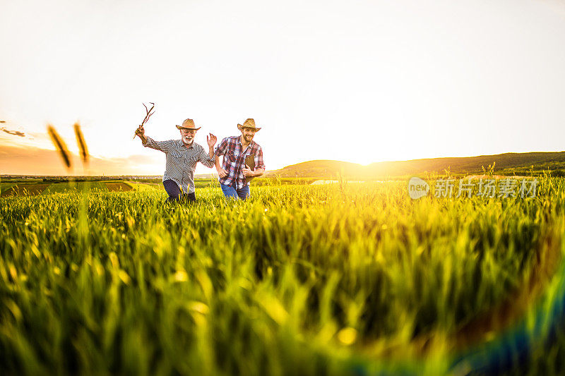 两个快乐的农民在农田里奔跑。