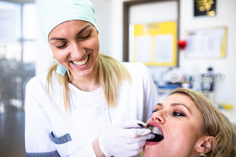 一位年轻的女牙医微笑着给病人留下牙科印模