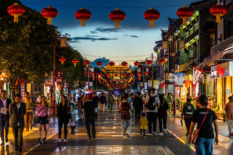 美丽的街景关渡古镇满是人与中国的灯笼和大门在远处在中国云南昆明晚上