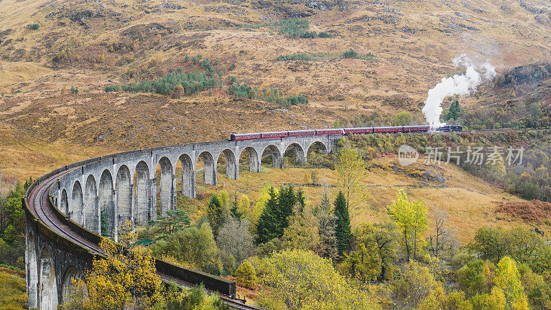 詹姆斯二世人的蒸汽火车经过苏格兰的格伦芬南高架桥，背景是群山。哈利波特电影里的火车。
