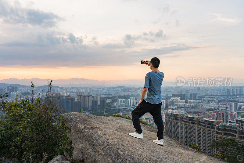 一名亚洲男子攀登成功后在岩石上自拍