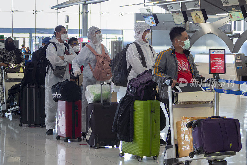 在泰国曼谷素万那普机场，亚洲乘客穿着防护服，在航班前办理登机手续。