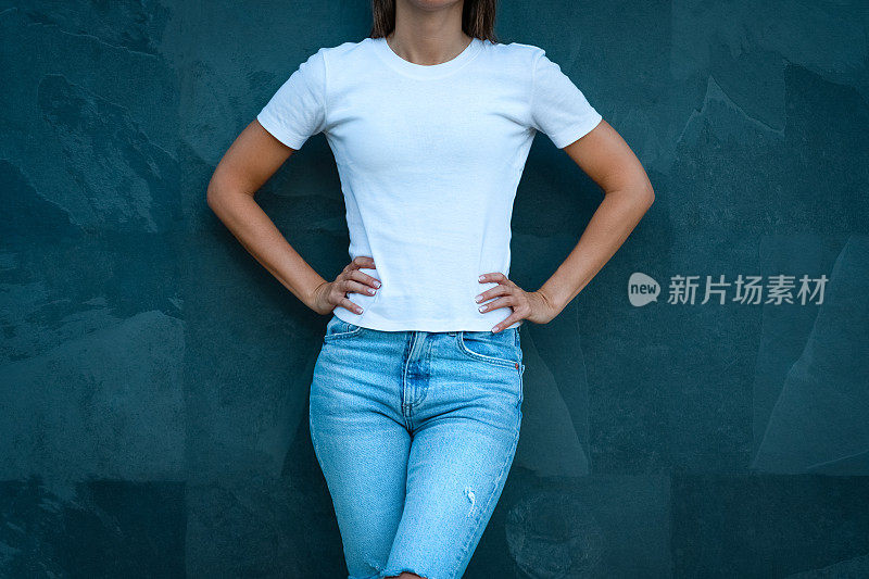 用于印刷设计的白色模型t恤。年轻时尚的女人穿着空白的白色t恤和蓝色牛仔裤在灰色的背景