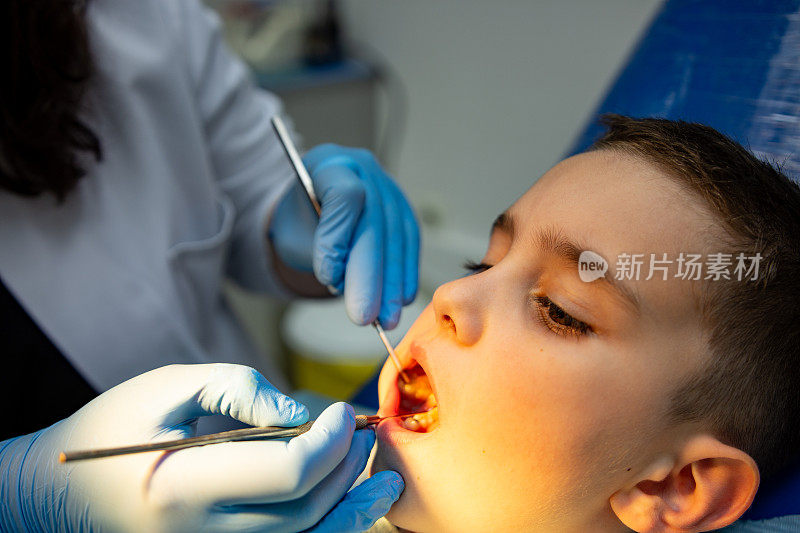 牙科医生检查坐在牙科椅子上的儿童牙齿