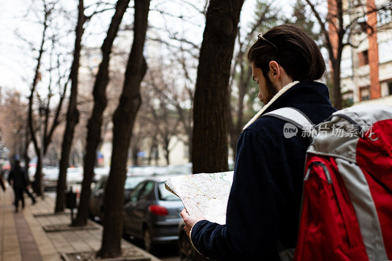 剪裁的镜头，一个英俊的年轻男子看着地图，而游览一个外国城市