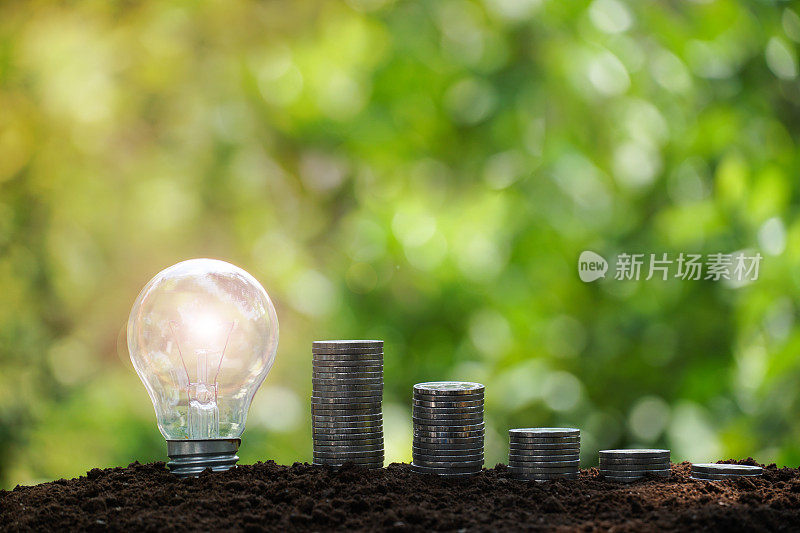 灯泡与硬币堆叠增加业务增长。企业可持续发展的财务理念。