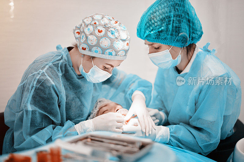 在一家牙科诊所，两名女牙医和牙科助理正在为一名穿着西装的病人进行治疗手术