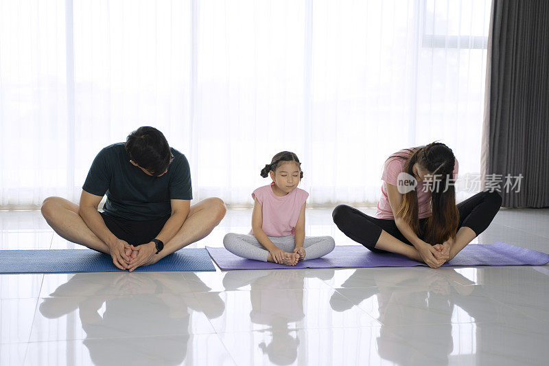 爸爸妈妈和他们的女儿在家里锻炼。