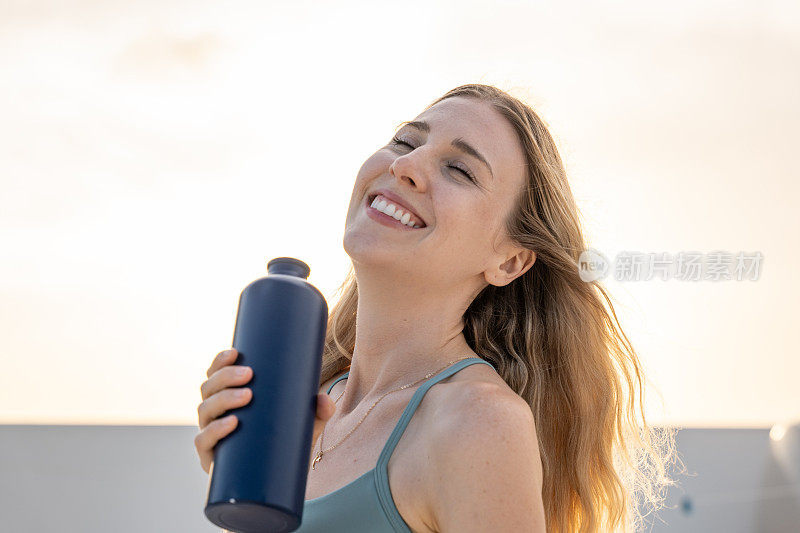 年轻女子用可重复使用的瓶子喝水的肖像