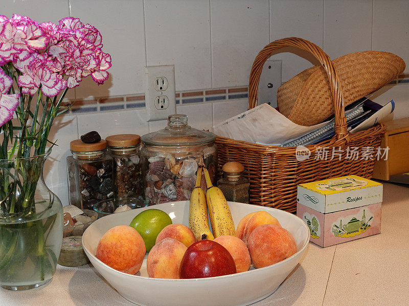 厨房柜台水果碗，鲜花，贝壳，和食谱盒。