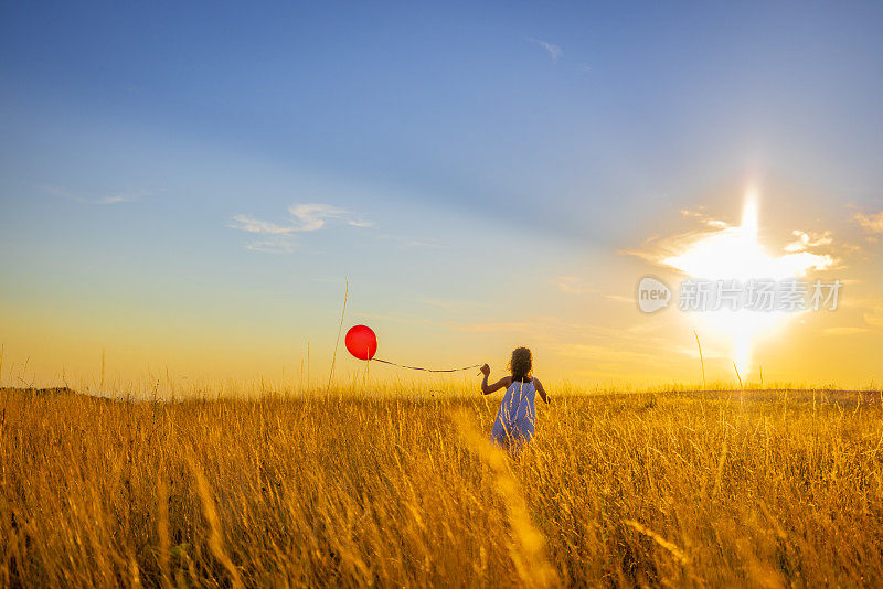 女孩玩气球，同时跑在草地上的草地对天空