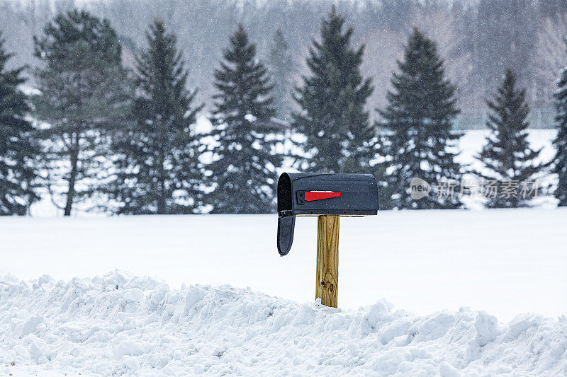 在冬季暴风雪中打开农村路边的邮箱
