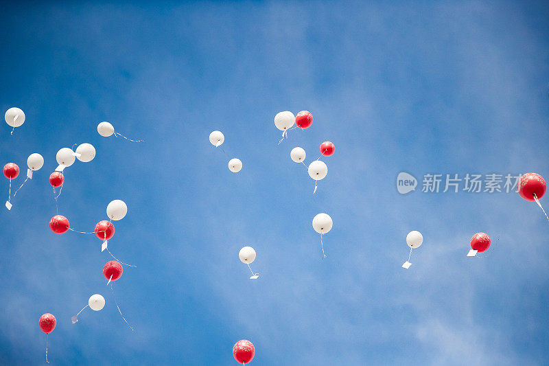 红色和白色的气球放飞到蔚蓝的天空