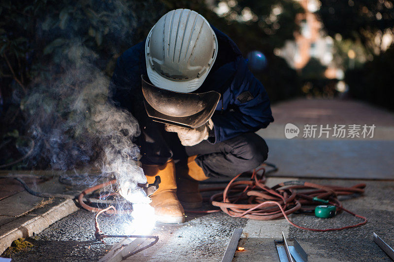 一名中年男性工人正在使用切割机和焊机