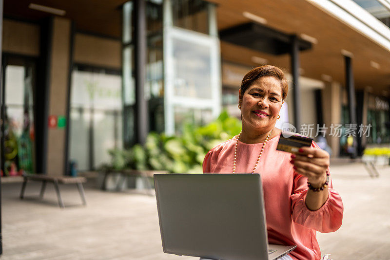 成熟女性在户外用笔记本电脑网购的照片