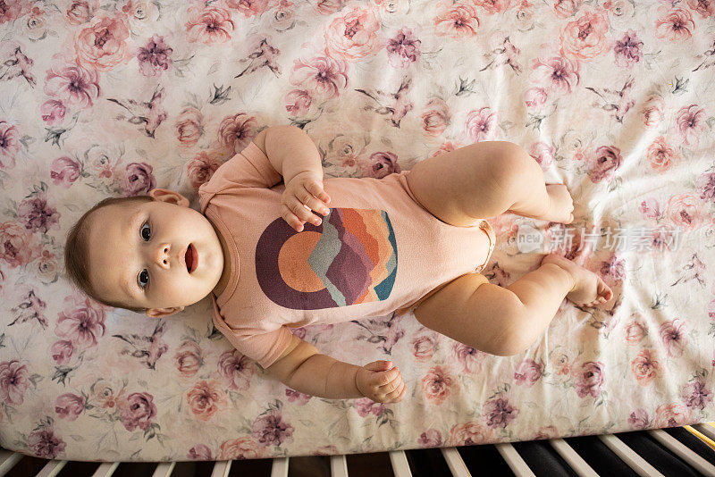 好奇的白人女婴躺在婴儿床上看着镜头