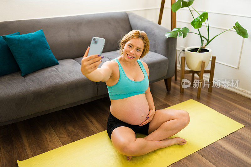 爱运动的孕妇在家里健身时自拍，看起来很开心