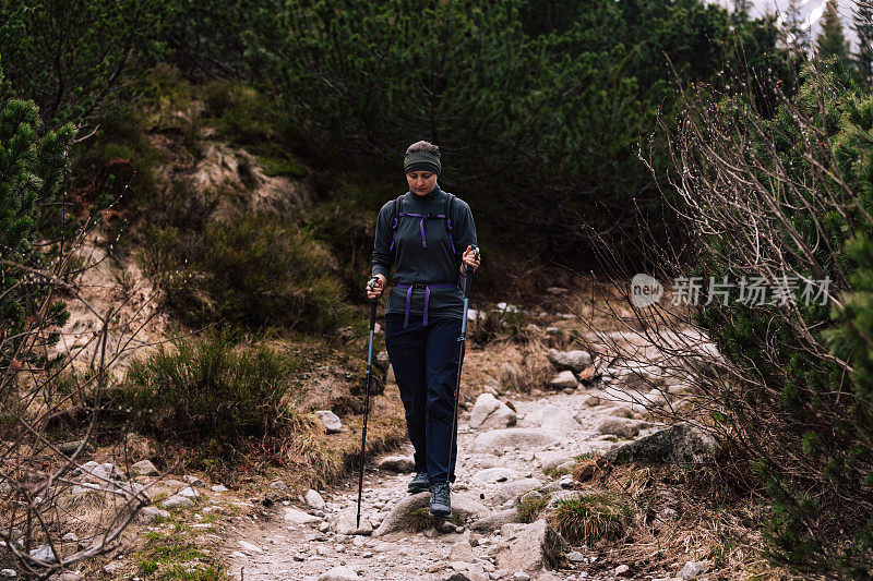 女人的女性肖像，谁在山中旅行。穿着保暖运动服在户外徒步旅行的人。生活方式摄影的人物和北欧徒步，旅游的概念。女孩是背包客，背包里装着旅游装备。