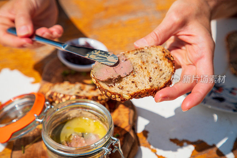 鹅肝酱用餐刀抹在全麦面包片上