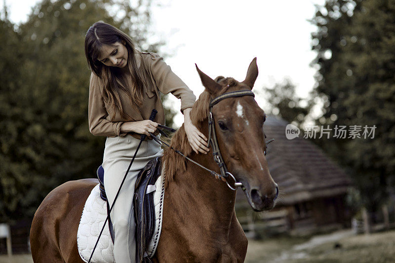 一个女人正在轻轻地抚摸着一匹马。在马学校学习骑马课程，接受马疗法，并与动物联系以缓解压力。享受一个自然的周末，获得情感上的回报。