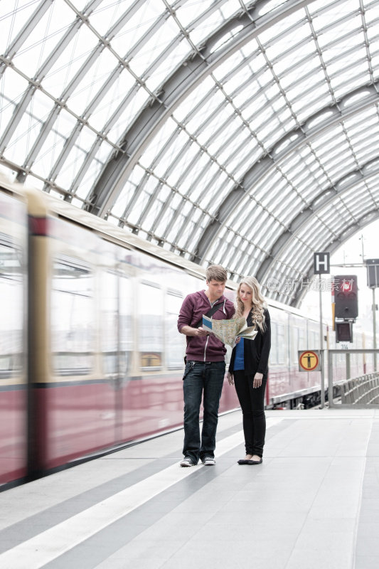 一对年轻夫妇站在火车站的月台上看地图