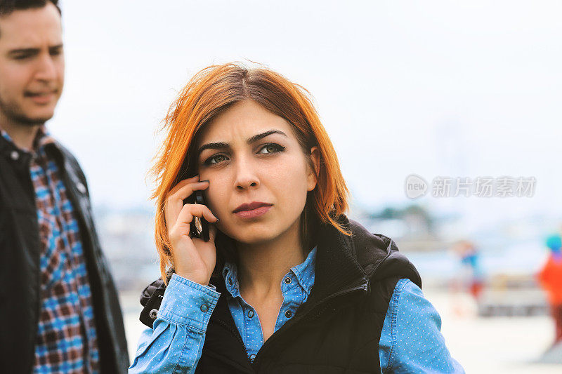 年轻的女人在公园里用手机聊天