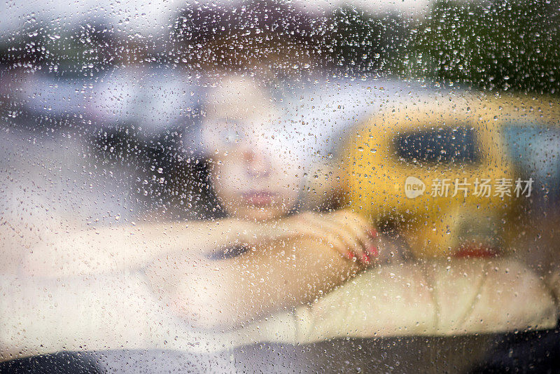 悲伤的女人在窗边看雨