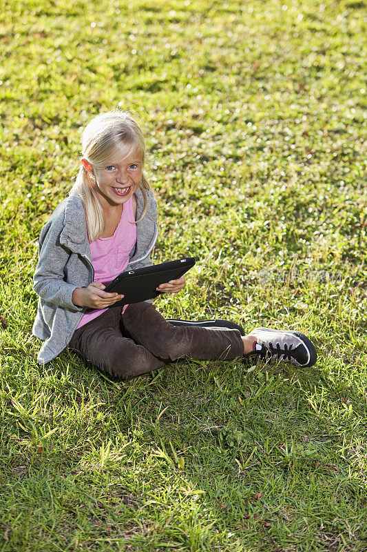 女孩坐在草地上用平板电脑