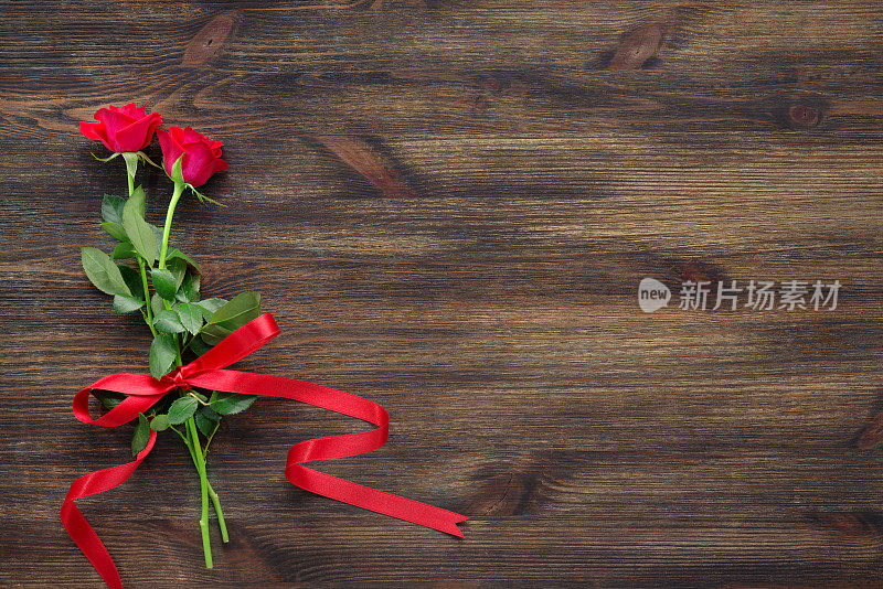 木制背景上的红玫瑰和丝带