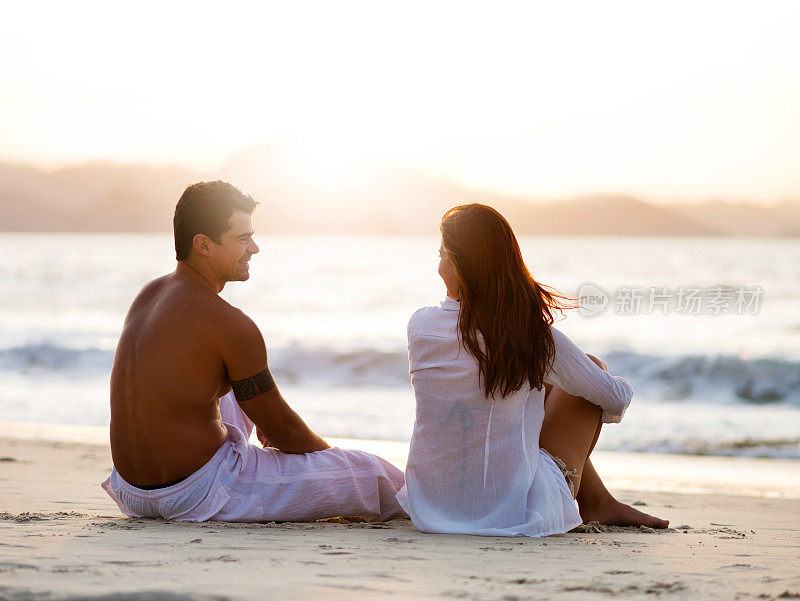 一对情侣在海滩上享受日落。