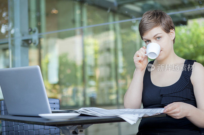 年轻的女商人喜欢喝早茶，看报纸