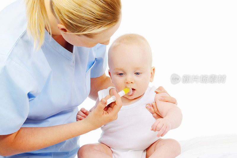 年轻的护士给婴儿男孩的药在白色的背景