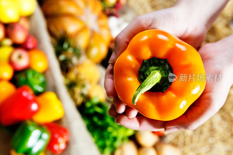农贸市场上，女人的手捧着一个甜椒